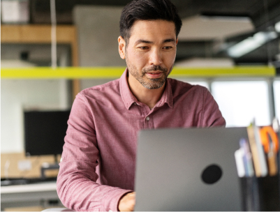 Middle aged Asian man in red shirt working on laptop